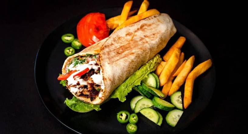 Pressed shawarma wrap in foil, cut to show meat, pickles, and toum inside fresh lavash, Patar Shawarma Glendale